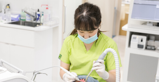 歯科衛生士が矯正（インビザライン）治療中の患者のメンテナンスをしている